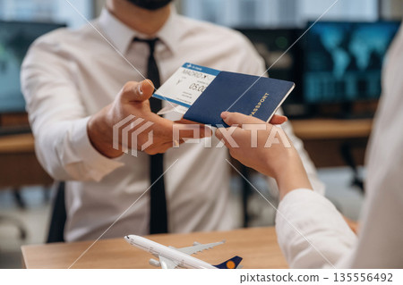 Travel and vacation time. Woman is giving boarding pass, tickets to airline company worker 135556492