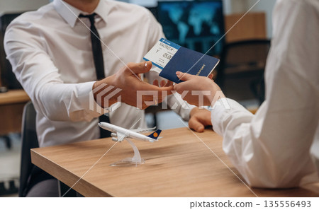 Woman is giving boarding pass, tickets to airline company worker Woman is giving boarding pass, tickets to airline company worker 135556493