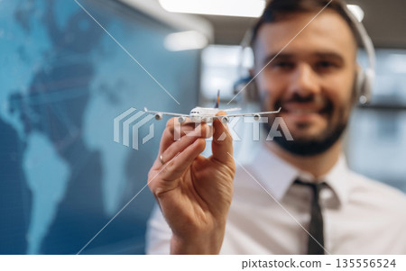Cheerful facial expression. Man is holding toy plane, in airline company Cheerful facial expression. Man is holding toy plane, in airline company 135556524