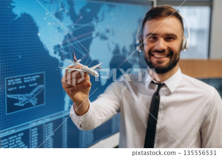 Standing and smiling. Man is holding toy plane, in airline company 135556531