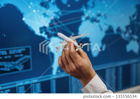Against blue map. Close up view of hand that is holding toy plane Against blue map. Close up view of hand that is holding toy plane 135556534