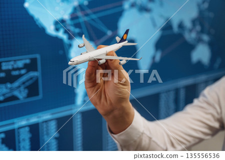 Against blue map. Close up view of hand that is holding toy plane Against blue map. Close up view of hand that is holding toy plane 135556536
