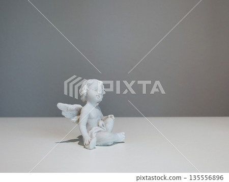 White ceramic angel figurine on white background for design. Faith, symbols, and traditions. White ceramic angel figurine on white background for design. Faith, symbols, and traditions. 135556896