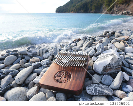 Kalimba musical instrument on stones by sea. Nature near mountains, music, and meditation. Relaxation and mental health. Kalimba musical instrument on stones by sea. Nature near mountains, music, and meditation. Relaxation and mental health. 135556901