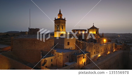 Malta, Comino island: Cittadella in Gozo at night, illuminating by warm lights create a captivating sunset scene that highlights historic architecture and travel destination. Drone flight 135556978