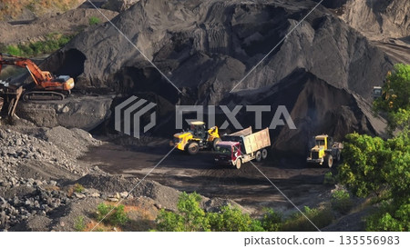Large open-pit quarry with massive excavators and dump trucks loading and hauling coal and ore, showing heavy machinery, earthmoving operations and dusty industrial landscape Large open-pit quarry with massive excavators and dump trucks loading and hauling coal and ore, showing heavy machinery, earthmoving operations and dusty industrial landscape 135556983