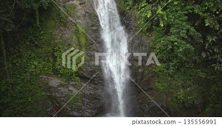Fiji, Nadi Waterfall: Crystal clear water cascading down a moss covered cliff, surrounded by lush greenery, creates a breathtaking rainforest scene. Wild nature landscape. Drone flight zoom in 135556991