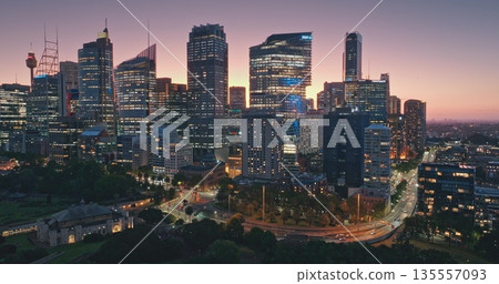 Australia, Sydney: Modern city background. Breathtaking aerial view of Sydney's illuminated skyline at dusk, night lights skyscrapers, city traffic, and iconic Sydney Tower. Drone flight 135557093