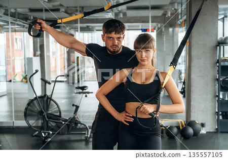Front view, standing and posing. Man and woman are in the gym together Front view, standing and posing. Man and woman are in the gym together 135557105