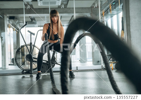 Active cross fit exercise with knots. Young woman is in the gym Active cross fit exercise with knots. Young woman is in the gym 135557227