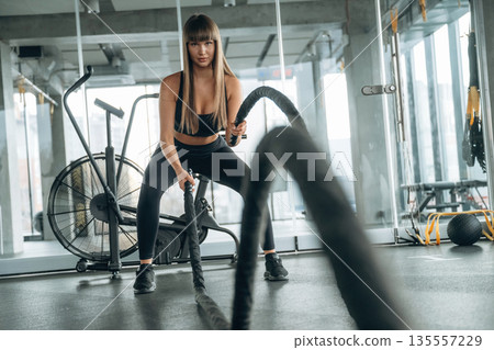 Active cross fit exercise with knots. Young woman is in the gym Active cross fit exercise with knots. Young woman is in the gym 135557229