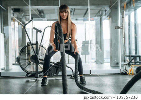 Active cross fit exercise with knots. Young woman is in the gym 135557230