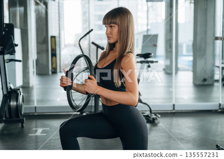 Elastic ring in hands. Young woman is in the gym 135557231
