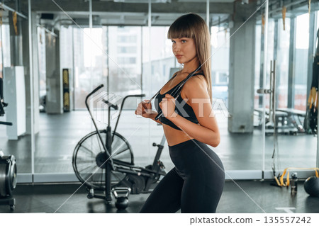 Jumping rope in hands and on the neck. Young woman is in the gym Jumping rope in hands and on the neck. Young woman is in the gym 135557242