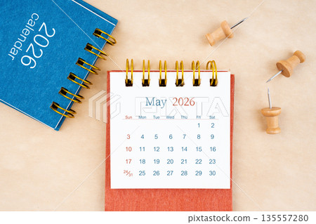 May 2026 desk calendar with wooden thumbtack on brown paper. 135557280