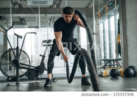 Endurance cross fit with knots. Man is in the modern gym Endurance cross fit with knots. Man is in the modern gym 135557306