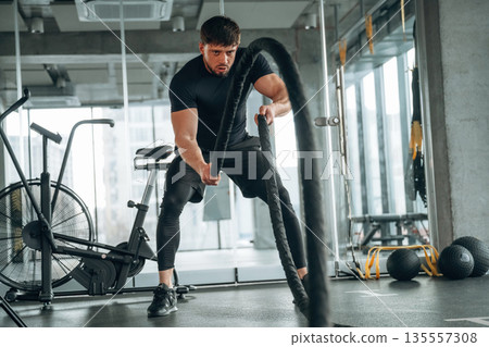 Focused of cross fit exercise with knots. Man is in the modern gym Focused of cross fit exercise with knots. Man is in the modern gym 135557308
