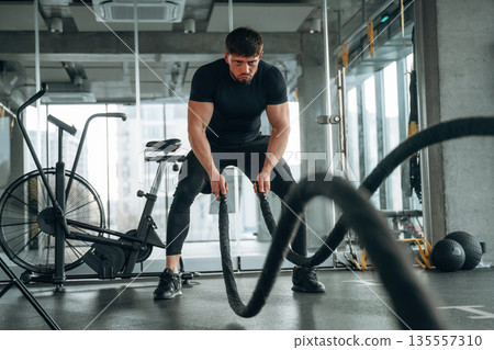 Focused of cross fit exercise with knots. Man is in the modern gym Focused of cross fit exercise with knots. Man is in the modern gym 135557310