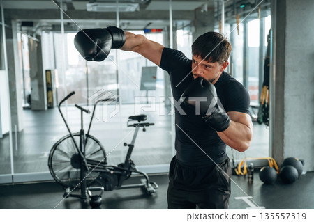 Punching, boxing training. Man is in the modern gym Punching, boxing training. Man is in the modern gym 135557319