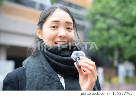 A woman speaking with a pin microphone in the street A woman speaking with a pin microphone in the street 135557762
