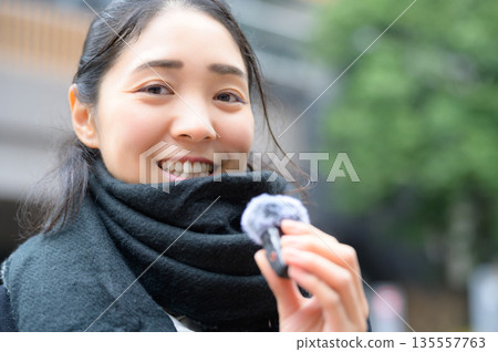 一名女子在街上用針式麥克風講話。 135557763