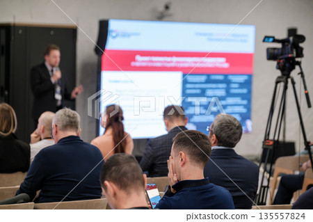 Business conference presentation with speaker audience and video crew in a modern seminar hall Business conference presentation with speaker audience and video crew in a modern seminar hall 135557824