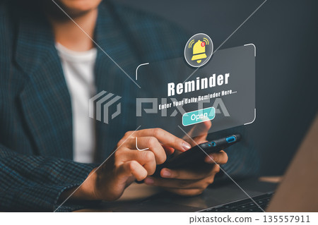 Close-up of hands holding smartphone with digital reminder notification, emphasizing productivity and organization. 135557911