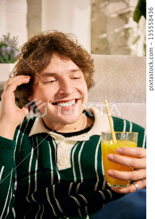 Smiling man holding glass of fresh juice at home Smiling man holding glass of fresh juice at home 135558436