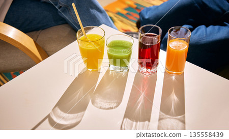 Assorted fresh juices in glasses on bright table with sunlight 135558439