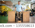 Determined disabled male in wheelchair doing upper body push ups workout using wooden blocks. 135558613
