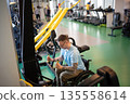 Motivated disabled man in wheelchair working on upper body strength with vertical fitness machine. 135558614