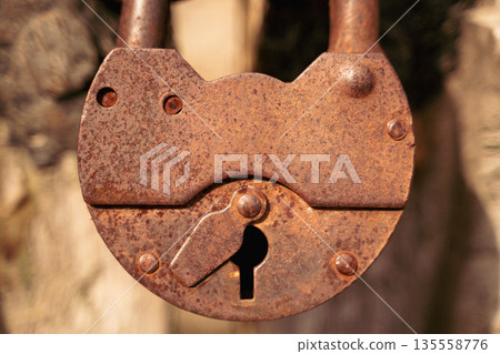 Close-up of a vintage rusty padlock with keyhole on old wooden door 135558776