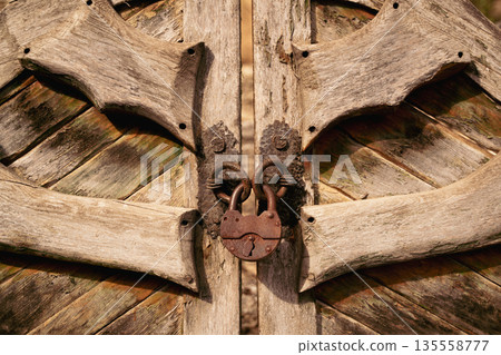Rustic wooden gate with weathered texture and antique iron lock 135558777