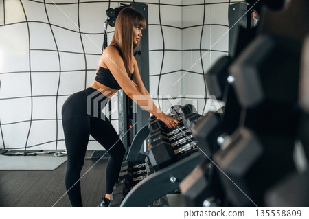 Taking the dumbbell. Young woman is in the gym 135558809