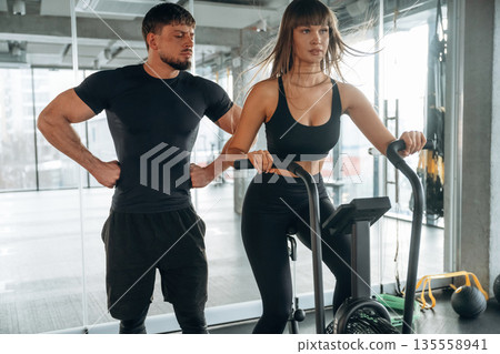 Cardio exercise, on bicycle. Man and woman are in the gym together Cardio exercise, on bicycle. Man and woman are in the gym together 135558941