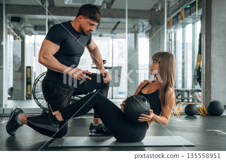 On the mat with ball. Man and woman are in the gym together 135558951