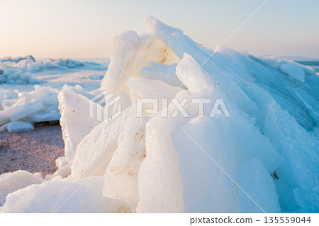 Frozen winter shoreline with stacked ice slabs Frozen winter shoreline with stacked ice slabs 135559044