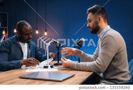 Active communication. Two radio presenters recording an audio broadcast in a studio Active communication. Two radio presenters recording an audio broadcast in a studio 135559260