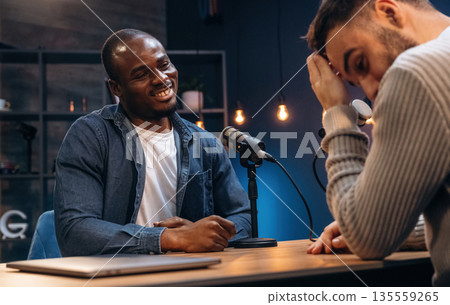 Two radio presenters recording an audio broadcast in a studio 135559265