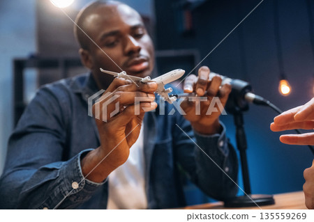 Showing toy plane. Two radio presenters recording an audio broadcast in a studio 135559269