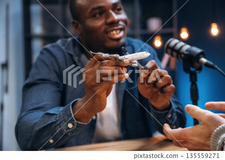 Showing toy plane. Two radio presenters recording an audio broadcast in a studio 135559271