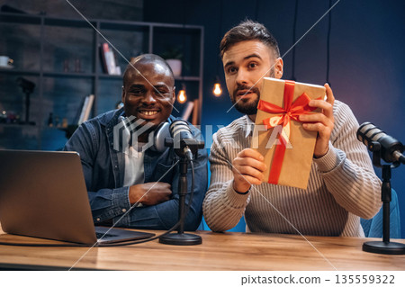 Christmas gift box. Two radio presenters recording an audio broadcast in a studio Christmas gift box. Two radio presenters recording an audio broadcast in a studio 135559322