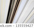 Closeup of layered print production sampler with textured paper swatches in various neutral tones and metallic 135559427