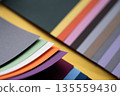 Closeup of layered print production sampler with textured paper swatches in various colors 135559430