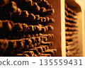 Closeup of dusty wine bottles stored in a dimly lit cellar 135559431