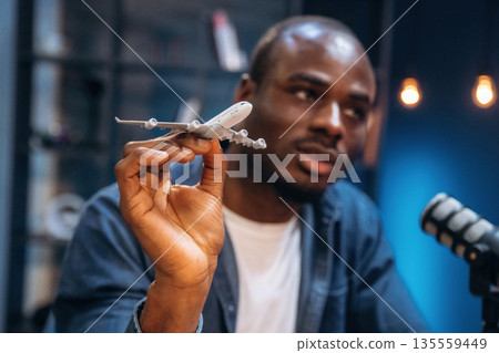 Model of plane in hand. Man is doing podcast in the studio Model of plane in hand. Man is doing podcast in the studio 135559449