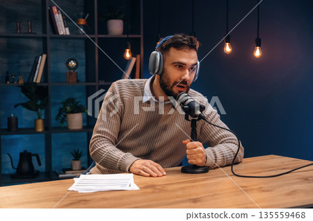 In headphones. Man is on the radio doing podcast live In headphones. Man is on the radio doing podcast live 135559468
