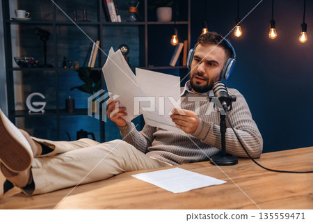 In headphones. Man is on the radio doing podcast live In headphones. Man is on the radio doing podcast live 135559471