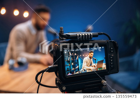 Camera is filming him. Man is on the radio doing podcast live 135559473