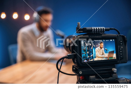 Camera is filming him. Man is on the radio doing podcast live 135559475